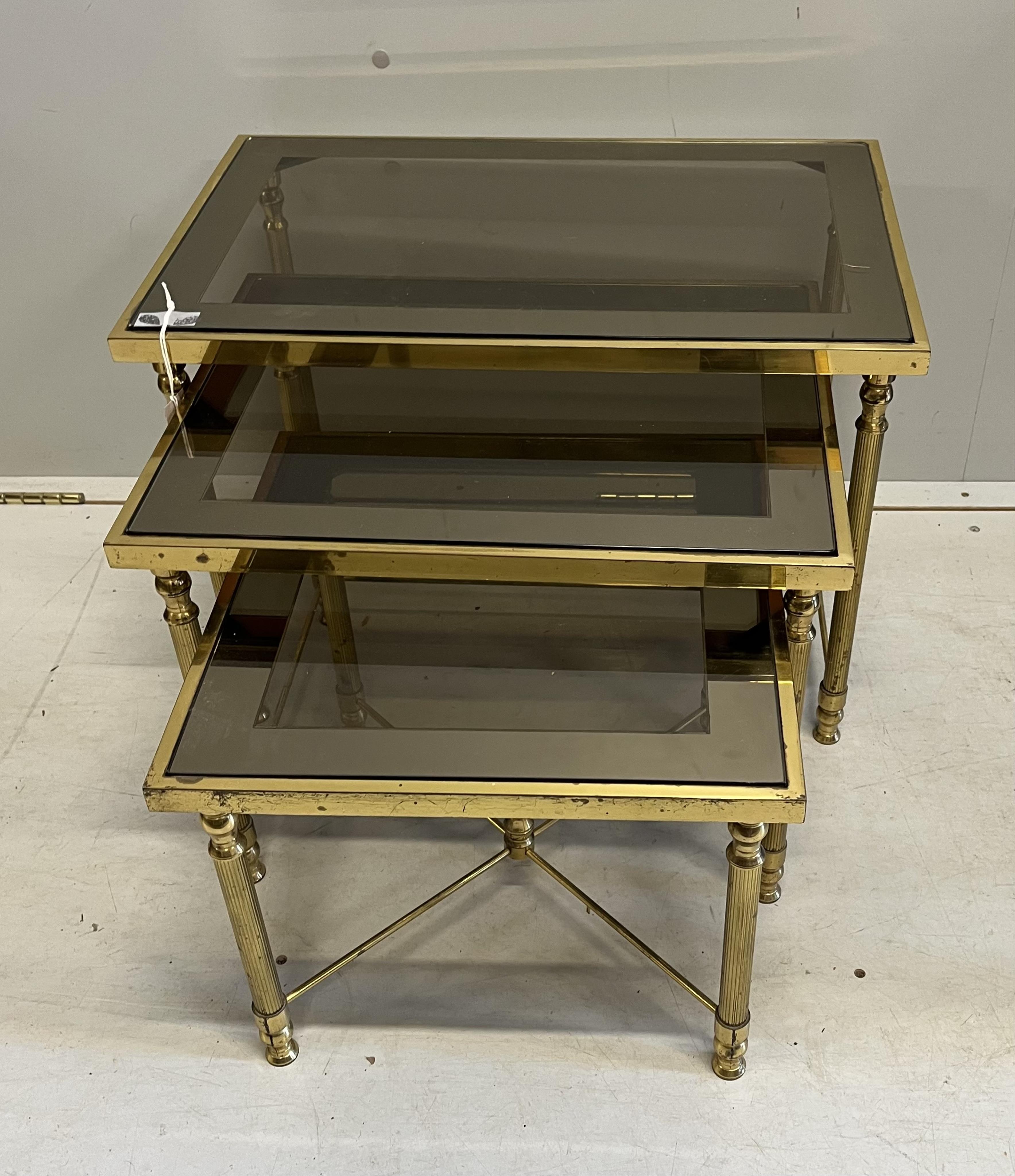 A Maison Jenson style nest of three brass smoked glass tables, width 57cm, depth 37cm, height 40cm